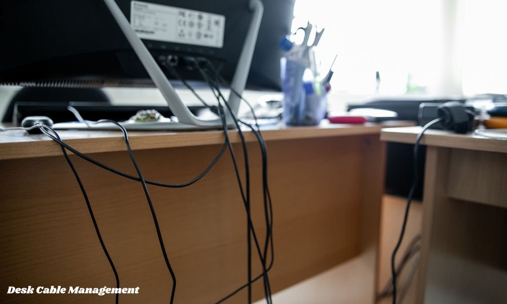 The Ultimate Guide to Desk Cable Management We have all been there. You spend hours picking out the perfect desk, setting up a sleek dual-monitor arrangement, and placing your mechanical keyboard just right. But then you step back, and what do you see? A chaotic web of black cords dangling beneath your workspace, hanging like synthetic cobwebs. It ruins the entire look. Beyond the ugly visuals, tangled cords are dust magnets, safety hazards, and major productivity killers. Every time you drop a phone charger behind the desk, you have to go on a fishing expedition under your workspace. Organizing your workspace does not require an engineering degree or a massive budget. With a simple plan and a few affordable tools, you can transform your desk into a clean, distraction-free environment. Here is how to achieve the best cable management for desk setups, step by step. Why Cable Management Actually Matters Before jumping into the solutions, it helps to understand why cord management is worth your time. A clean workspace is not just about showing off on social media—it directly impacts your daily life. Mental Clarity: Clutter in your physical environment leads to mental clutter. A clean sightline helps you focus on work or gaming without passive visual distractions. Device Protection: Cables bent at harsh angles or constantly pulled by gravity wear out much faster. Tidy routing extends the life of your expensive gear. Easier Cleaning: Dust accumulates quickly around tangled wires. Elevating cords off the floor lets you sweep or vacuum underneath in seconds. Safety First: Dangling wires are a tripping hazard for you, and an tempting chew toy for pets. Unplug Everything and Audit Your Setup The biggest mistake people make is trying to organize cables while everything is still plugged in. It simply does not work. You end up wrapping new ties over old knots. Start with a completely blank slate. Unplug every single power brick, display cord, and USB cable. Lay them out on your floor or bed. Ask yourself three questions as you sort through them: Do I actually use this? (If a wire is not attached to an active device, store it in a drawer.) Is this cable too long? (If you have a 10-foot HDMI cable for a monitor sitting two feet from your computer, swap it for a shorter 3-foot version.) Can I go wireless? (A wireless mouse, keyboard, or headset immediately cuts three major wires off your desktop.) Mount the Surge Protector Under Your Desk The fundamental secret to a invisible cable setup is simple: get the power strip off the floor. When your surge protector sits on the floor, every single device wire has to drop down from the desk surface to reach it. This creates a vertical waterfall of mess. Instead, mount your power strip to the underside of your desk. You can do this using heavy-duty double-sided mounting tape, velcro strips, or small screws if your surge protector has keyhole slots on the back. By anchoring the power source directly beneath your workspace, every cord stays hidden underneath, and only one main power cord ever needs to reach the wall outlet. Essential Tools: Trays, Raceways, and Clips To get professional results, you need a few basic accessories. You do not need to buy all of them, but combining two or three will solve almost any routing challenge. Tool Best Used For Installation Difficulty Under-Desk Cable Trays Holding large power bricks, excess wire slack, and power strips Easy to Moderate (Screws or Clamps) J-Channel Raceways Guiding cables horizontally along the back or underside of a desk Very Easy (Adhesive backing) Adhesive Cable Clips Directing single wires (like phone chargers or mouse cords) along fixed paths Very Easy (Peel and stick) Velcro Cable Ties Bundling multiple cords traveling in the same direction Extremely Easy (Reusable) Braided Cable Sleeves Grouping 4-5 wires dropping down to the floor into one neat tube Easy (Zipper or split design) Under-Desk Cable Trays: The Workspace Workhorse If you only buy one tool for your setup, make it an under-desk cable tray or basket. These metal mesh or plastic channels attach to the underside of your desk board. They act as a hidden shelf for all the ugly parts of your setup: bulky laptop power bricks, extra cord lengths, and power strips. Instead of carefully folding every inch of extra cord, you can simply roll up the excess wire and drop it into the tray. Out of sight, out of mind. Wire mesh trays are particularly great because they allow proper airflow around power adapters, preventing heat buildup. Routing Cables Behind the Monitor Monitors are usually the highest point of clutter because they require power and display connections (HDMI or DisplayPort) that hang directly down the wall. To hide these wires: Attach your monitor to a monitor arm. Monitor arms elevate your screen and almost always come with built-in channels or clips inside the arm itself. If using the stock stand, run the cables directly behind the center pillar. Secure them to the back of the stand using small black velcro ties. Keep the wires hugging the back of the monitor stand until they pass below the desk surface. From there, lead them directly into your under-desk tray. Managing Standing Desks (Sit-Stand Setups) If you use an adjustable standing desk, cable management requires one extra rule: you must account for movement. If you tie your cables too tightly while the desk is lowered, raising the desk will yank cords out of your computer or snap port connectors. Leave Slack at the Wall: Ensure the main power cable running from your under-desk surge protector to the wall outlet is long enough to reach comfortably when the desk is at its absolute highest setting. Use a Cable Spine: A flexible cable spine or umbilical sleeve anchors to the bottom of the desk and resting on the floor. It bends smoothly like a spine as the desk rises and lowers, keeping the main vertical drop looking intentional and organized. Why You Should Ditch Plastic Zip Ties It is tempting to grab a pack of cheap plastic zip ties from the hardware store, but avoid them. Zip ties are permanent. The moment you decide to swap your keyboard, buy a new monitor, or adjust your desk layout, you will have to carefully cut through every single zip tie with scissors—risking accidentally slicing your device cords in the process. Always choose reusable Velcro ties or micro-straps instead. They are cheap, hold cords firmly, and take two seconds to undo whenever you need to re-route a single wire. Dealing with Desktop Peripherals and Chargers Not all cables can live underneath the desk. You still need access to phone chargers, headphone cables, and keyboard wires on the top surface. To keep top-of-desk clutter under control: Use Desktop Cable Anchor Clips: Stick small silicone cable anchors near the back edge of your desk. These hold the heads of your charging cables in place so they don't slide off onto the floor when unplugged. Consolidate with a Wireless Charging Pad: Instead of having three separate charging cords for your phone, watch, and earbuds, use a single 3-in-1 wireless charging pad. Consider Coiled Keyboard Cables: If you use a wired mechanical keyboard, a custom coiled cable adds aesthetic appeal while keeping excess length tight and spring-loaded rather than sprawling across your mousepad. Common Cable Management Mistakes to Avoid Even with the best gear, a few common mistakes can ruin your hard work: Pulling Cables Too Tight: Always leave a tiny bit of slack near device ports. Constant tension damages both the cord head and the internal port on your computer or monitor. Mixing Power and Audio Lines: Running unshielded audio cables directly alongside high-voltage power bricks can sometimes cause low electronic buzzing or static interference in your speakers or headphones. Forgetting to Label Devices: Before you bundle ten black cables into a single sleeve, attach small sticky tags or labels to both ends. When you need to unplug a specific display six months from now, you won't have to guess which wire to pull. Maintenance: Keeping it Tidy Long Term Cable management is not a one-and-done event; it is a habit. Over time, you will add a new USB hub, switch your web camera, or plug in temporary devices. To maintain a clean setup: Adopt a "one-in, one-out" rule. If you plug in a new permanent accessory, route its cord properly immediately instead of telling yourself you will do it "later." Do a 5-minute quarterly audit. Every few months, check under the desk to sweep away dust and re-fasten any adhesive clips that might have loosened over time. Final Thought Achieving the best cable management for desk setups isn't about perfection or making every single wire vanish into thin air. It is about creating a clean, functional system that keeps your workspace tidy, safe, and easy to maintain over time. You don't need to do it all in one afternoon either. Start simple: unplug the mess, mount a power strip underneath your desk surface, and bundle loose cords together with velcro straps. You will be amazed at how much larger, cleaner, and more inviting your workspace feels once the wire chaos is gone. Give it a try, and enjoy the instant boost to your daily productivity!